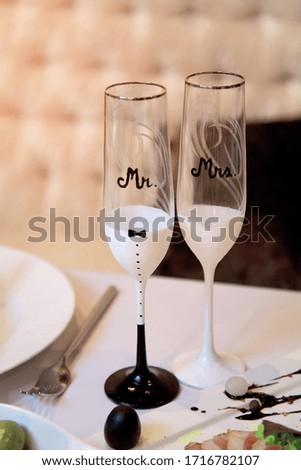 Two glasses of champagne are on the wedding table. The glasses are next to each other and they say Mr and Mrs