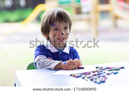 Children Education Concept, Lovely Boy Sitting at his Desk Painting