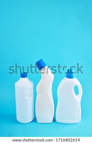 blank chemicals bottles over blue background. vertical orientation. cleaning service concept.