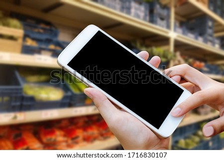 woman hand hold and touch screen smartphone or cellphone over blurred shopping center or super market background.