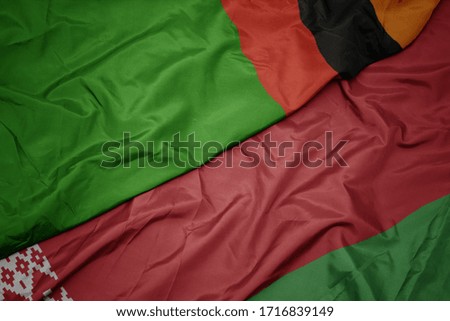 waving colorful flag of belarus and national flag of zambia. macro