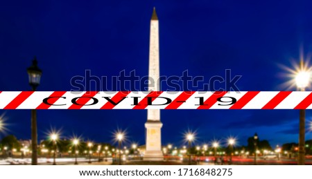 Coronavirus in Paris, France. Covid-19 sign on a blurred background. Concept of COVID pandemic and travel in Europe. Place de la Concorde and  Obelisk of Luxor at night