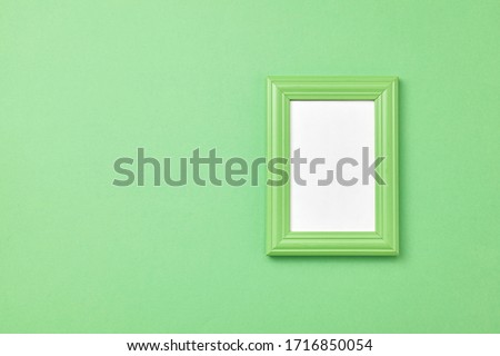 Green frame for painting or picture on coloful background Top view