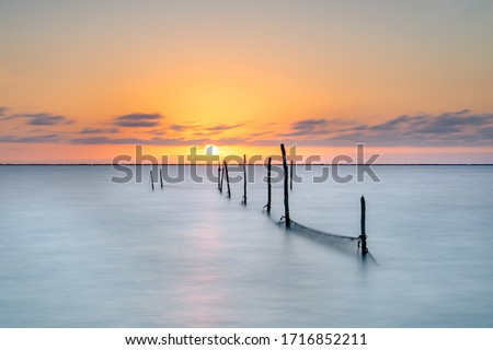 Long exposure picture of a fyke at the inner lake ijsselmeer, in the netherlands with an endless view over the hroizon at dusk