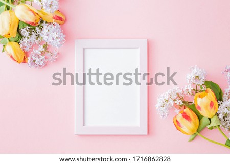 Mockup frame with branches of lilac and yellow tulips on a pink background