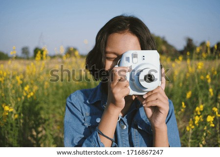 Happy Asian young girl enjoy taking picture at flower garden.