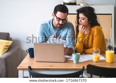 Worried couple looking at their bills at kitchen table stock photo