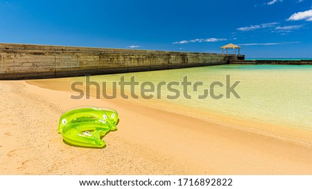 inflatable beach toy laying on a tropical encased beach with clear turquoise see-through waters on a sunny day