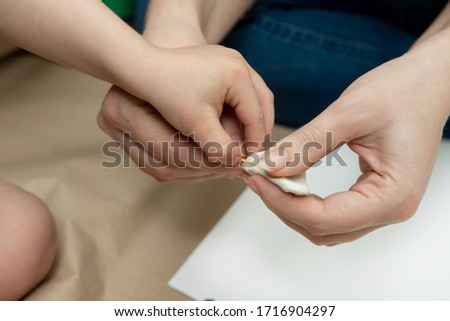 a small child with mom kneads a white piece of plasticine. children's crafts to school, kindergarten.