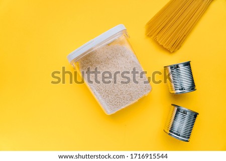 Food supplies crisis food stock for coronavirus quarantine isolation period in yellow background. different food in aluminum cans, Rice, pasta. Food delivery, Donation. top view. Copy space.
