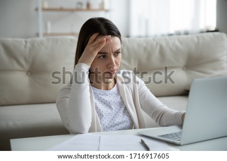 Unhappy young woman sit at home work on laptop frustrated by slow Internet connection on gadget, upset distressed female have operational computer problems, stressed by unpleasant email or message Royalty-Free Stock Photo #1716917605