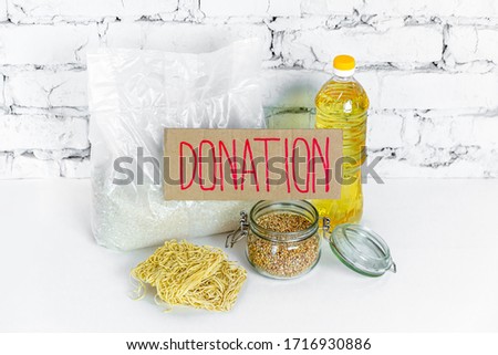 Food collection for donations, on a white brick background. Anti-crisis stock of essential goods for the period of quarantine isolation. Food delivery, coronavirus. The shortage of food