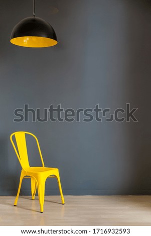 Living room wall mock up with dark grey wall and bold yellow chair and lamp. Illuminating Yellow and Ultimate Gray, colors of the year 2021