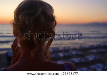 Woman taking a photo of sunset on the beach