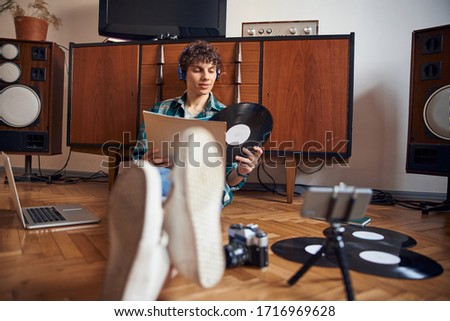 Handsome guy sitting on the floor and holding vinyl record stock photo