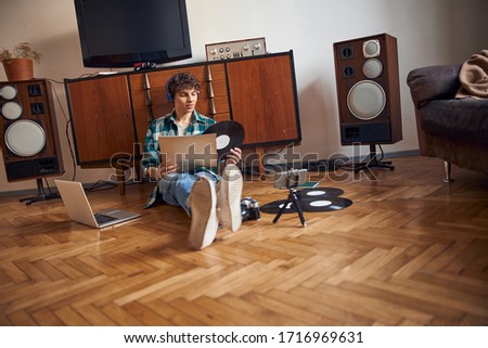 Attractive guy sitting on the floor and holding vinyl record stock photo
