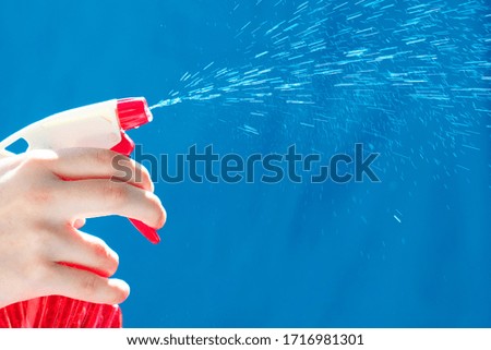 Spray atomizer in female hand. Spray with a water jet close-up. Housework concept