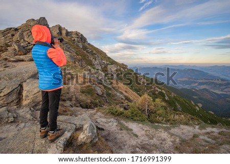 Young child boy hiker taking pictures in mountains enjoying view of amazing mountain landscape.