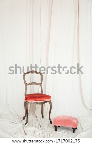 A chair and a small stool with velvet upholstery on a light linen background