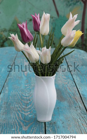 White tulips in a vase on a green wooden table. Beautiful gentle bouquet.