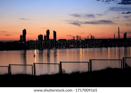 sunset over an industrial city behind a lake
