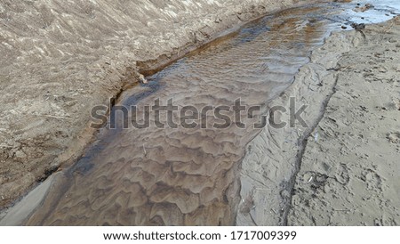 clean creek flowing through the sand in the daytime