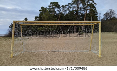 old torn football goal on empty sandy beach