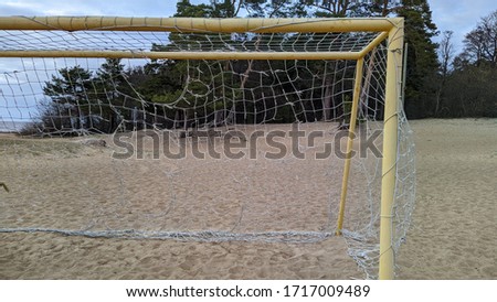 old torn football goal on empty sandy beach