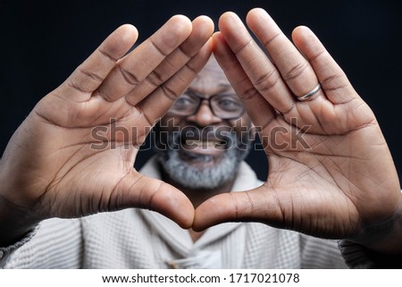 Two hands of a bearded man are framing his face