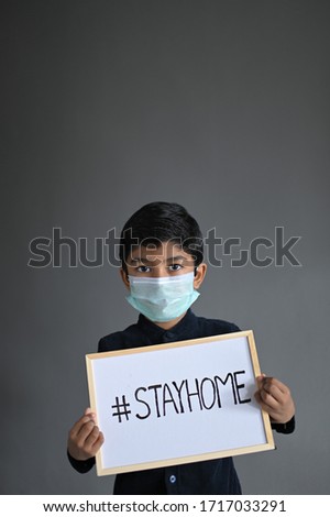 STAY HOME. Asian Boy wearing Medical Masks and show sign Stay home, looking at camera to Prevent Disease and Dust, pm.5, Stay at home quarantine coronavirus pandemic prevention. Royalty-Free Stock Photo #1717033291