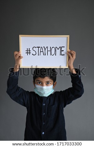 STAY HOME. Asian Boy wearing Medical Masks and show sign Stay home, looking at camera to Prevent Disease and Dust, pm.5, Stay at home quarantine coronavirus pandemic prevention. Royalty-Free Stock Photo #1717033300