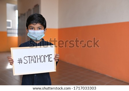 STAY HOME. Asian Boy wearing Medical Masks and show sign Stay home, looking at camera to Prevent Disease and Dust, pm.5, Stay at home quarantine coronavirus pandemic prevention. Royalty-Free Stock Photo #1717033303