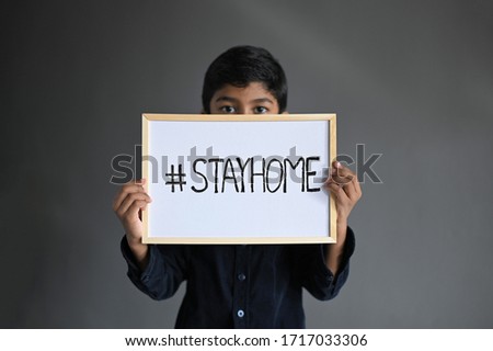 STAY HOME. Asian Boy wearing Medical Masks and show on sign "Stay home" board selective focus, Stay at home quarantine coronavirus pandemic prevention. Royalty-Free Stock Photo #1717033306