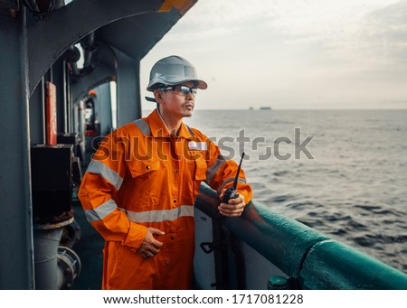 Filipino deck Officer on deck of vessel or ship , wearing PPE personal protective equipment. He holds VHF walkie-talkie radio in hands. Dream work at sea Royalty-Free Stock Photo #1717081228
