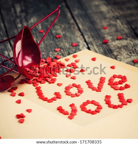 Red Tiny Hearts from letter, on wooden table, square image