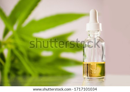 Glass bottle with cbd oil on white background with marihuana leaf. Hemp  based cosmetics and beauty products. 
 Royalty-Free Stock Photo #1717101034
