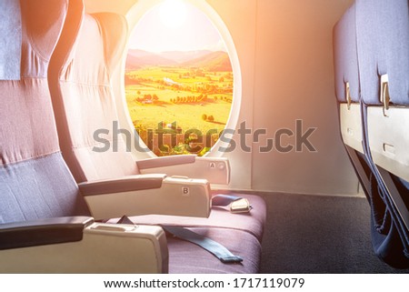 Beautiful countryside landscape viewed from porthole of commercial aircraft with empty seats