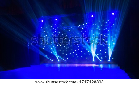 Blurred show background. Empty stage and sparkling stage lights. Blue light beams spotlights on stage at time of entertainment show. Laser and lights show in the dark. Royalty-Free Stock Photo #1717128898