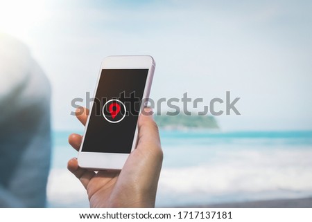 Woman hand using smart phone with navigator location point at beach background. Technology interenet and travel adventure concept. Vintage tone filter effect color style.