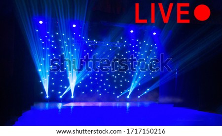Text LIVE and red circle on blurred show background. Empty stage and sparkling stage lights at time of entertainment show. Concept live performance concert on the Internet, online show. Royalty-Free Stock Photo #1717150216