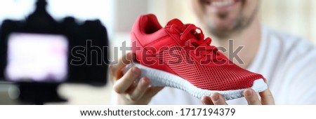 Male product reviewer tells his subscription in an online broadcast how to recognize signs of originality and fake sports sneakers closeup. Consultant seller education concept