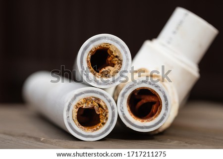 Old broken sludge polypropylene plumbing pipes with red rust and limescale. Corrosion, sludge and hard water concept. Rust broken water pipes Royalty-Free Stock Photo #1717211275