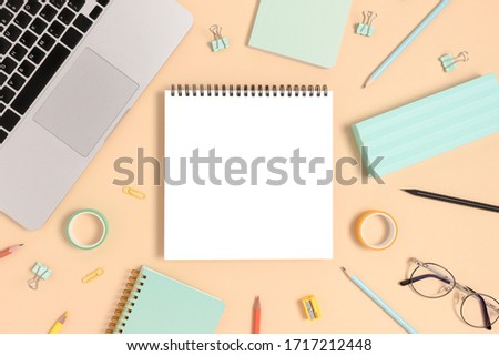 Blank notepad mockup. Top view of laptop and stationery on a yellow pastel background. Workspace concept.