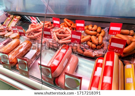 Showcase with boiled and smoked sausage in store. Refrigerator shelves with different meat products