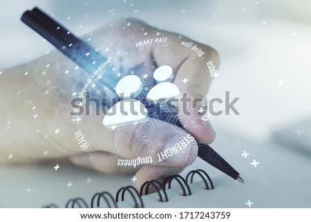 Creative abstract people icons hologram and man hand writing in diary on background, life and health insurance concept. Multi exposure