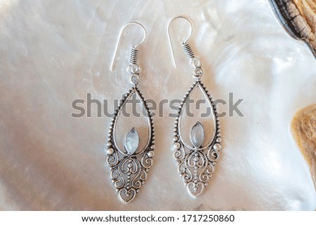 Brass metal pair of beautiful elegant earrings on white natural shell background