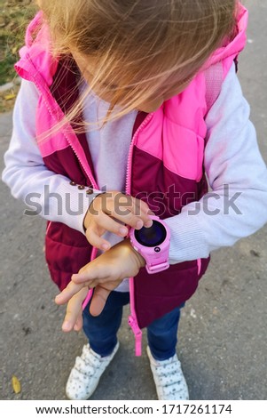 Little blonde school girl using her smart watch. Concept: the latest technology for child safety and parental peace