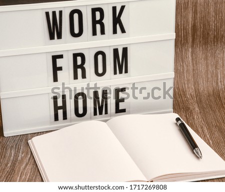 lightbox with text WORK FROM HOME with notebook pen and headphones, copy space wooden table background, quarantine and isolation HOME OFFICE, coronavirus, europe