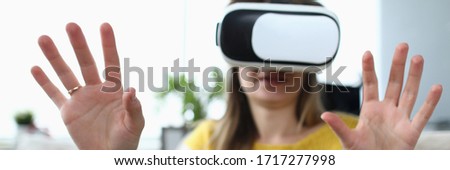 Close-up view of happy young woman using virtual reality headset. Real picture and surprised female with hands up. Future technology and entertainment concept