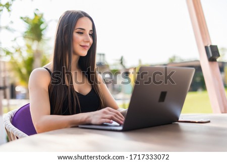 Beautiful girl with a laptop working in beach cafe